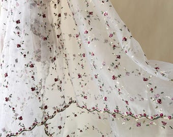 May include: White sheer fabric with delicate embroidery of small burgundy flowers and green stems. The floral pattern is evenly distributed across the fabric, creating a soft, romantic aesthetic. The edges are finished with a detailed floral border.