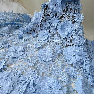 Pu&ograve; includere: Tessuto di pizzo blu chiaro con un motivo floreale. Il tessuto ha un effetto 3D con fiori in rilievo.