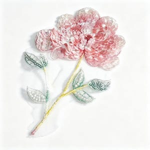 Puede incluir: Un parche de aplicación floral con una flor rosa de múltiples pétalos cubierta de lentejuelas brillantes. El tallo es amarillo y las hojas están detalladas con pequeñas cuentas de color verde claro y blanco, sobre una base de malla blanca transparente.