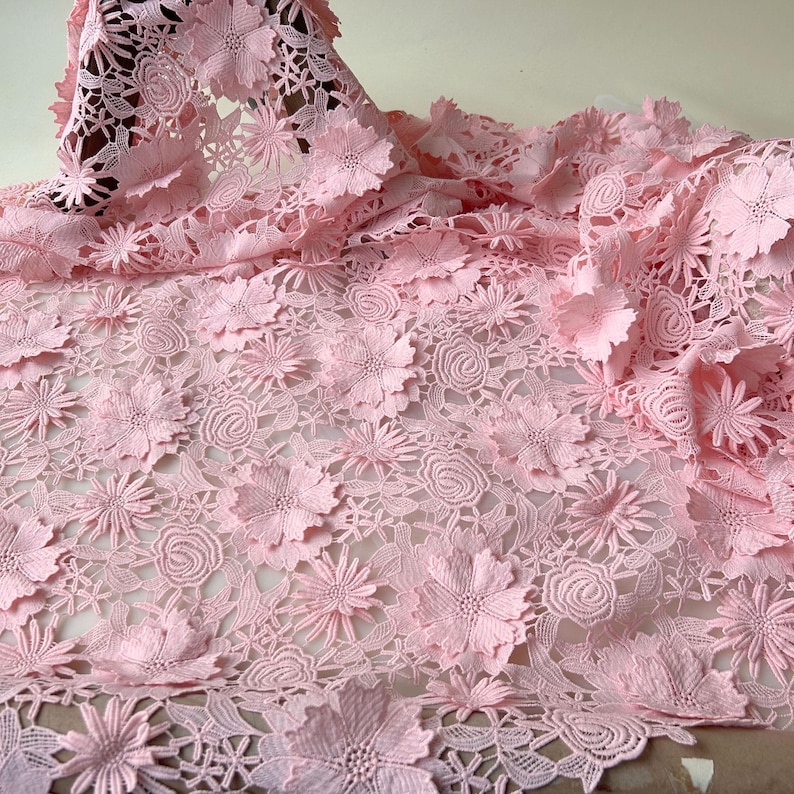 Pu&ograve; includere: Tessuto di pizzo floreale rosa con un design delicato e intricato. Il pizzo presenta fiori 3D in rilievo e un delicato motivo traforato.