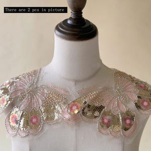 May include: Two decorative shoulder pieces with a floral design. The pieces feature pink, gold, and silver sequins, beads, and embroidery. The text "There are 2 pcs in picture" is visible in the image.