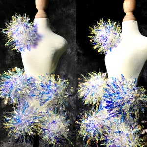 May include: A white mannequin is decorated with iridescent blue and yellow fluffy trim. The trim is arranged in a layered, cascading design, creating a whimsical and festive look.