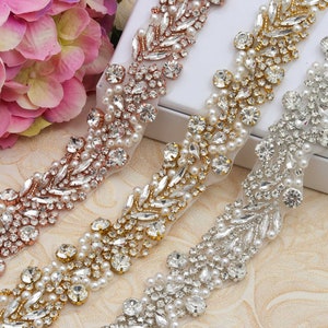 May include: Three beaded trims with a wavy design. The trims are made of clear rhinestones, pearls, and gold or rose gold accents. The trims are on a white background.
