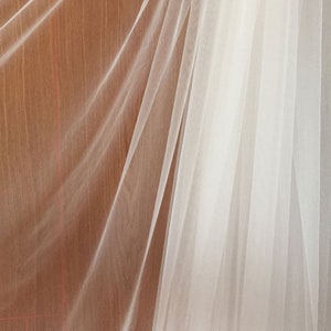 May include: White sheer fabric draped over a wooden surface. The fabric is translucent and has a delicate texture.