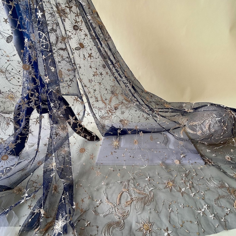 May include: Navy blue tulle fabric with gold and silver embroidered stars and moons. The fabric is sheer and delicate.