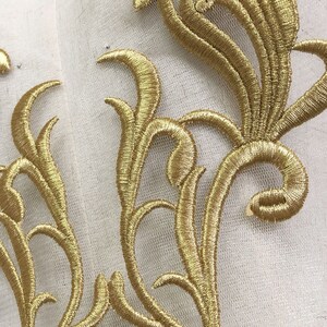 May include: Gold embroidered lace applique with a floral design. The lace is delicate and intricate, with a variety of swirls and curves. It would be perfect for adding a touch of elegance to any project.