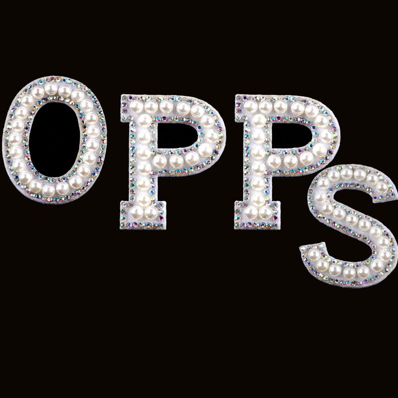 Puede incluir: Letras blancas adornadas con perlas que deletrean "OPPS" sobre un fondo negro.