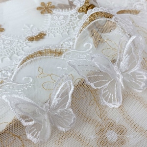 May include: White lace fabric with gold embroidery and white butterfly appliques.