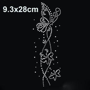 Puede incluir: Un diseño de mariposa de strass blanco con un tallo floral, que mide 9,3 cm por 28 cm.