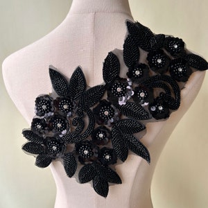 May include: Black beaded and sequined floral applique with rhinestone accents. This embellishment is ideal for adding a touch of elegance to clothing, accessories, or home decor projects.