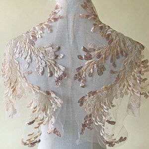 Może przedstawiać: Delikatna, przezroczysta tkanina z kwiatowym wzorem ozdobionym cekinami w kolorze różowego złota. Tkanina idealnie nadaje się do dodania odrobiny elegancji do każdego projektu.