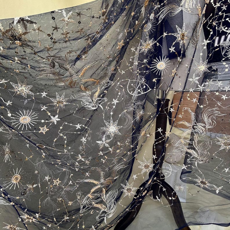 May include: Black sheer fabric with gold and silver embroidered stars and moons. The fabric has a delicate, airy feel.