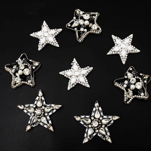 May include: Eight star-shaped embellishments with pearl and rhinestone accents.  Four are black with white accents and four are white with black accents.
