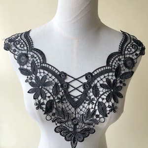 Può includere: Bordino in pizzo nero con un delicato motivo floreale e un design a croce al centro. Questo bordino è perfetto per aggiungere un tocco di eleganza a qualsiasi capo.