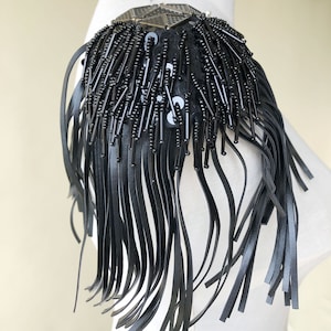 Pode incluir: Franja de franja de couro preto com um enfeite de metal em forma de estrela. A franja tem aproximadamente 15 cm de comprimento.