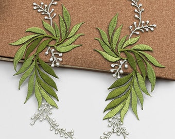 May include: Two green and white embroidered floral appliques with a leafy design. The appliques are perfect for adding a touch of nature to clothing, bags, or home decor projects.