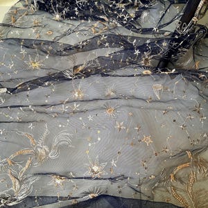 May include: Black tulle fabric with gold embroidered stars and other celestial designs.