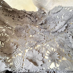 Pu&ograve; includere: Tessuto di pizzo floreale grigio con un design delicato e intricato. Il pizzo presenta una variet&agrave; di forme e dimensioni di fiori, creando un look bellissimo ed elegante.