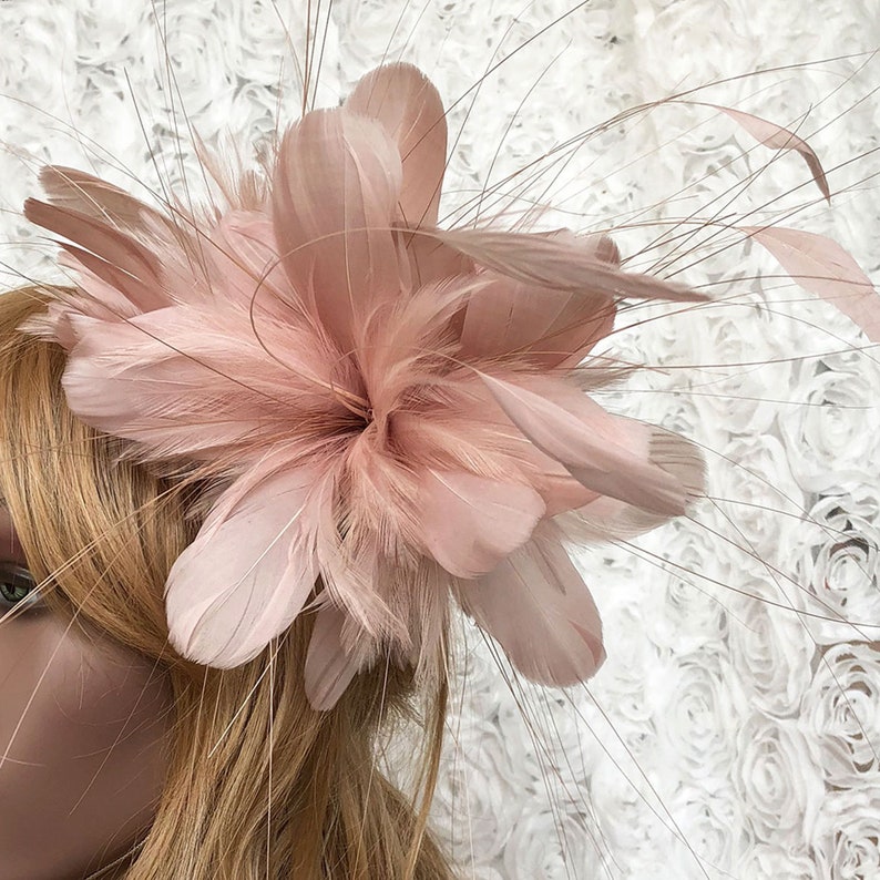 Puede incluir: Un fascinador de plumas rosa rubor con un dise&ntilde;o floral. El tocado presenta plumas grandes y suaves y delicados acentos tenues. El accesorio est&aacute; dise&ntilde;ado para ser usado en la cabeza, perfecto para ocasiones especiales.