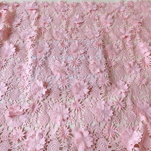 Pu&ograve; includere: Tessuto di pizzo rosa con un motivo floreale. Il tessuto ha un motivo delicato e intricato con fiori in rilievo.