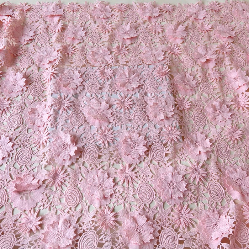 Pu&ograve; includere: Tessuto di pizzo rosa con un motivo floreale. Il tessuto ha un motivo delicato e intricato con fiori in rilievo.