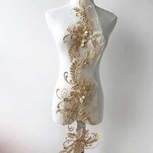 May include: Gold floral applique with beaded accents on a sheer fabric background. This delicate embellishment is perfect for adding a touch of elegance to clothing, accessories, or home decor projects.
