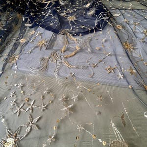 May include: Black sheer fabric with gold embroidered stars and a constellation design.