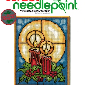 May include: Needlepoint kit titled "Stained Glass Candles" featuring a design of two red candles with flames and holly berries. The kit includes 100% wool yarn, a needle, and instructions. It fits a 9 x 12 inch frame.