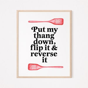 May include: A white framed print with a red spatula and the text "Put my thang down, flip it & reverse it".