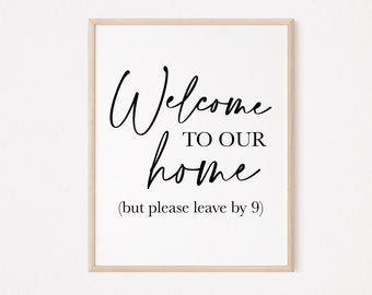 May include: A white framed print with black text that reads "Welcome to our home (but please leave by 9)"