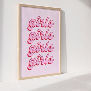 May include: A framed print with a pink background and the word "girls" repeated four times in a red and pink font.