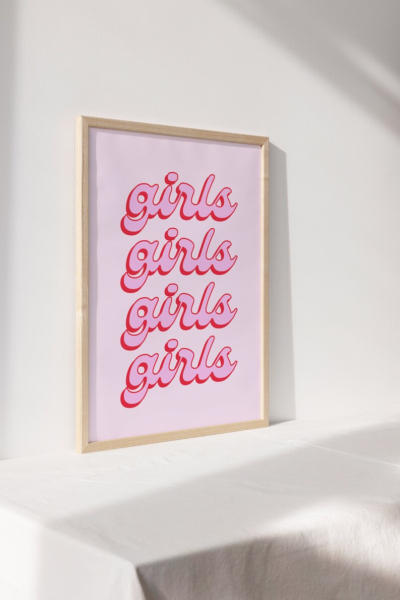 May include: A framed print with a pink background and the word "girls" repeated four times in a red and pink font.