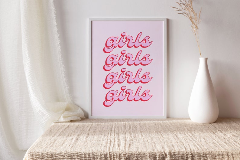 May include: A framed print with a pink background and the word "girls" repeated four times in a red, cursive font.
