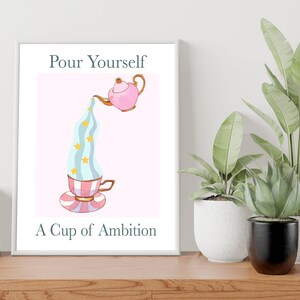Pu&ograve; includere: Una stampa incorniciata bianca con una teiera rosa che versa un liquido blu e bianco con stelle dorate in una tazza da t&egrave; a righe rosa e bianche. Il testo "Pour Yourself A Cup of Ambition" &egrave; sotto l'immagine.