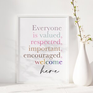 K&ouml;nnte beinhalten: Ein wei&szlig;er gerahmter Druck mit dem Text "Everyone is valued, respected, important, encouraged, welcome here" in bunten Farben auf wei&szlig;em Hintergrund.