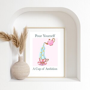 Pu&ograve; includere: Una teiera rosa versa un liquido blu e bianco a righe con stelle gialle in una tazza da t&egrave; con un piattino a righe rosa e bianco. Il testo "Pour Yourself A Cup of Ambition" &egrave; sotto l'immagine.