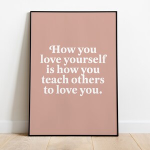 Op de afbeelding: Een roze ingelijste poster met de tekst "How you love yourself is how you teach others to love you."