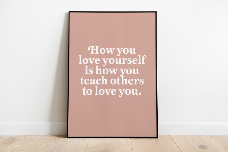 Op de afbeelding: Een roze ingelijste poster met de tekst "How you love yourself is how you teach others to love you."