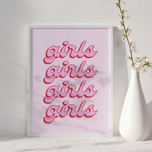 May include: A white framed print with the word "girls" repeated four times in a pink and red font on a light pink background.