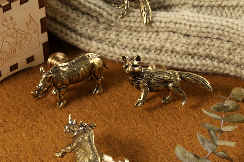 Op de afbeelding: Vier dierfiguren van messing, een neushoorn, een vos en twee andere neushoorns, op een bruin oppervlak. De figuren zijn gedetailleerd en hebben een realistisch uiterlijk.
