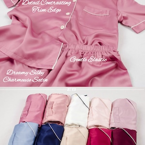May include: A set of pink satin pajamas with white trim. The pajamas have a button-up top with a pocket and a drawstring bottom. The text "Attention to Detail Contrasting Trim Edge", "Dreamy Silky Charmeuse Satin", and "Gentle Elastic" is visible on the image. The pajamas are folded and wrapped, ready to be gifted.