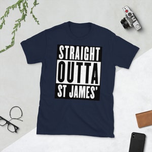 May include: Navy blue t-shirt with the text "STRAIGHT OUTTA ST JAMES'" in a white, bold font inside a black rectangle. The shirt is a crew neck style.