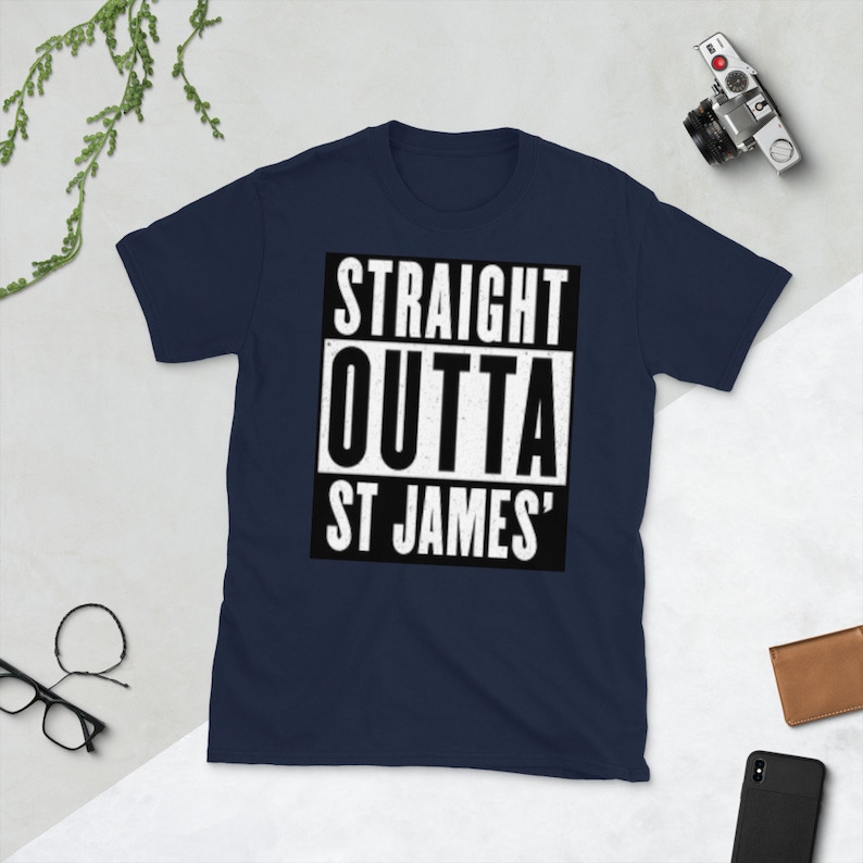 May include: Navy blue t-shirt with the text "STRAIGHT OUTTA ST JAMES'" in a white, bold font inside a black rectangle. The shirt is a crew neck style.