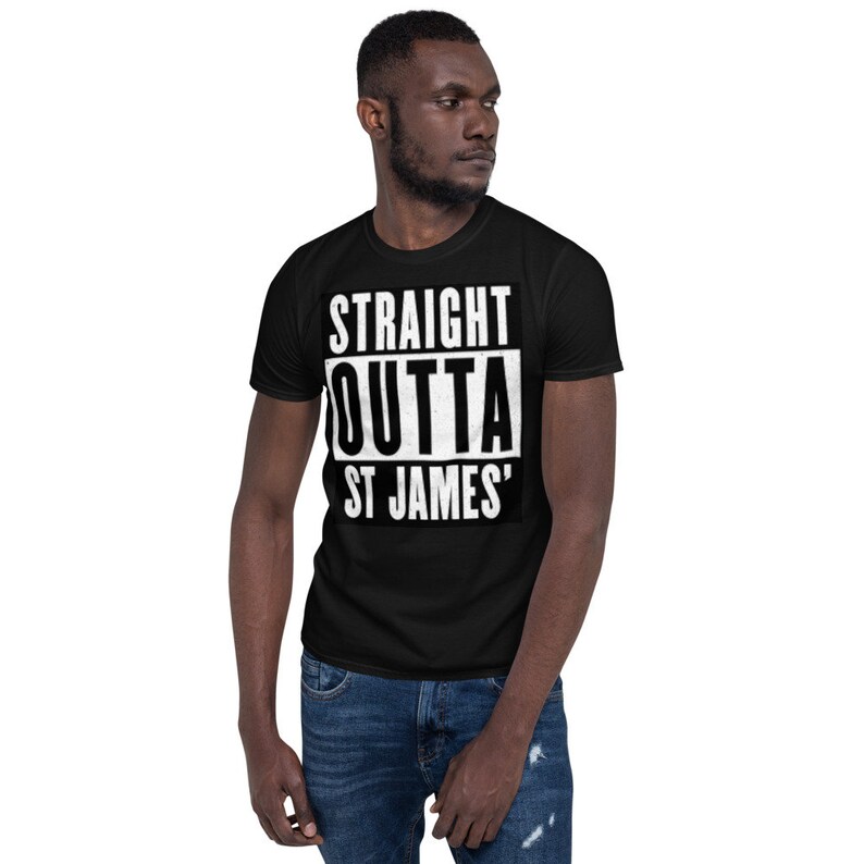 May include: Black t-shirt with the white text "STRAIGHT OUTTA ST JAMES'" in a bold, blocky font. The shirt is a classic crew neck style and is worn by a person in blue jeans.
