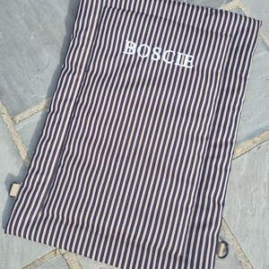 Cotton dog settle mat with shoulder strap and popper fastening. The mat for dogs helps with training a dog or puppy to settle. It makes a perfect gift for dogs and tool for puppy training. The puppy settle training pad is available is different colours and made easy to carry.