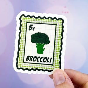May include: A sticker in the shape of a postage stamp featuring a green broccoli illustration. The stamp reads "5¢" at the top and "BROCCOLI" at the bottom. The stamp has a green dotted border and a white background.
