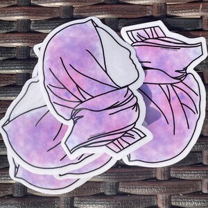 May include: Three purple and white watercolour stickers of a woman wearing a headscarf. The stickers are layered on top of each other.