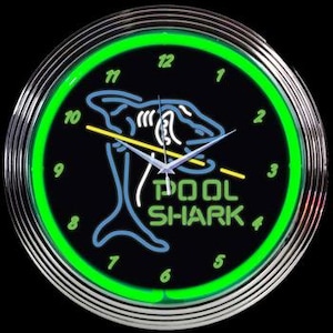 May include: A neon clock with a green frame and a black face. The clock features a blue and white shark with a pool cue in its mouth. The text "POOL SHARK" is written in green below the shark.