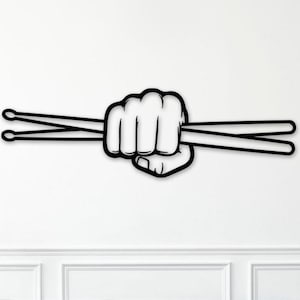 May include: Black and white wall art featuring a clenched fist holding two drumsticks. The artwork is a minimalist design, perfect for a music room or a drummer's space. The drumsticks are parallel and extend to the left.