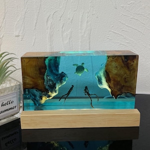 Könnte beinhalten: Eine rechteckige Harzskulptur mit einer blauen und grünen Ozeanszene. Die Skulptur zeigt zwei Taucher, eine Meeresschildkröte und einen Holzsockel.